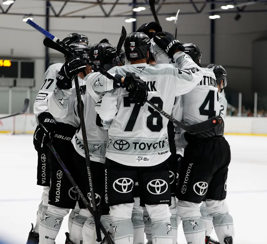 Hockeyspillere i hvite trøyer med svarte numre og Toyota-logoet feirer på isen.