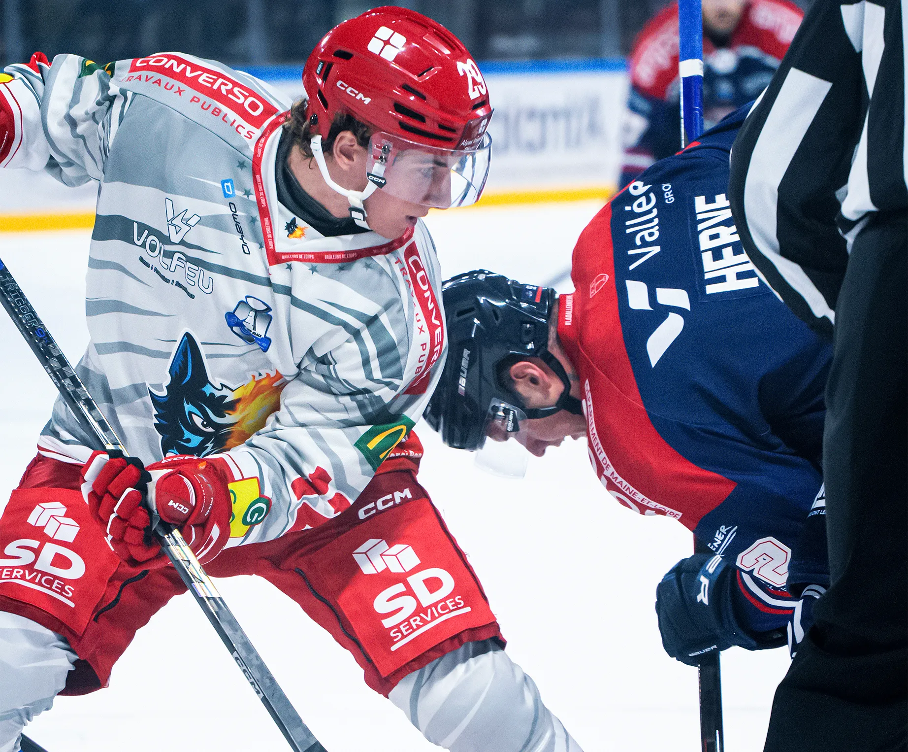 To ishockeyspillere står overfor hverandre, klare for ansikt til ansikt, den ene iført en grå og rød drakt med et ulvedesign.