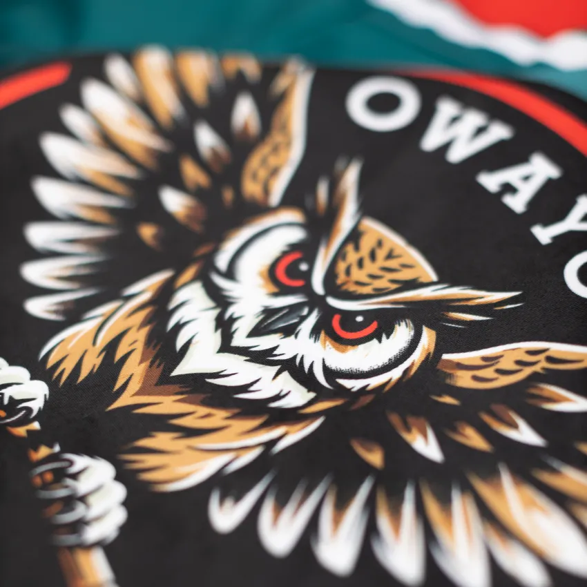 Et detaljert, fargerikt design av et ulemotiv på svart bakgrunn, vist på et sportsklær fra owayo.