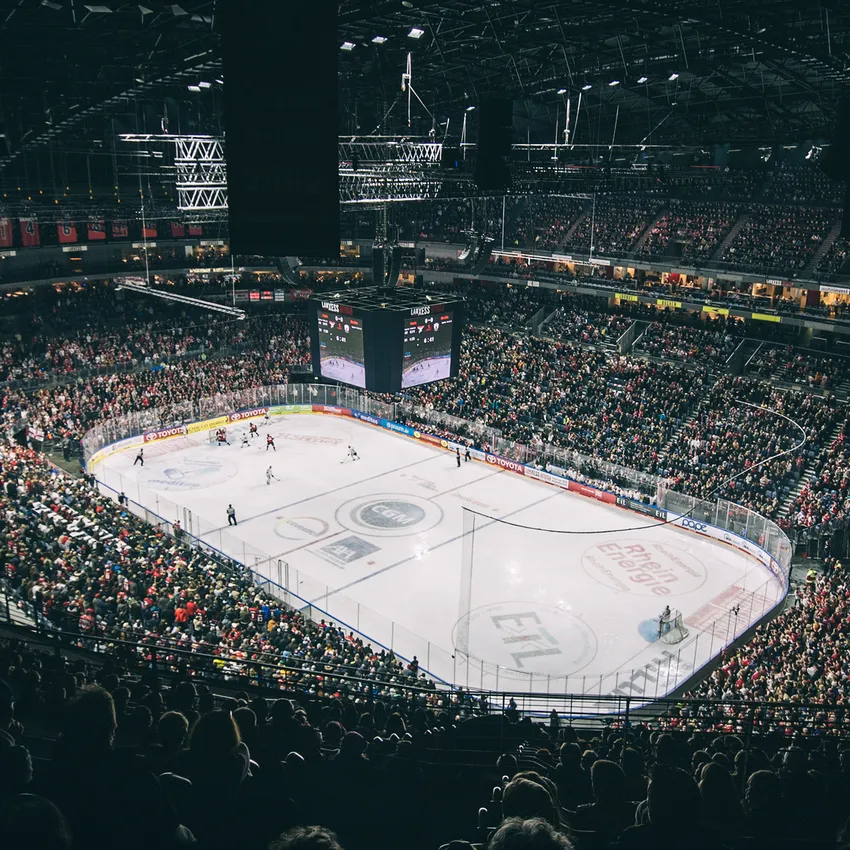 En fullsatt ishockeyarena med jublende fans, synlig isbane og en stor skjerm i bakgrunnen.