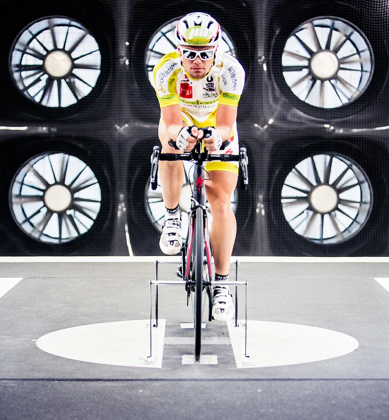 En syklist i aerodynamisk posisjon på en sykkel i en vindtunnel, for å teste ytelsen til tilpasset sportsutstyr.