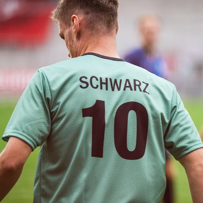 En spiller har på seg en mintgrønn fotballdrakt med nummer 10 og navnet 'SCHWARZ' på ryggen.