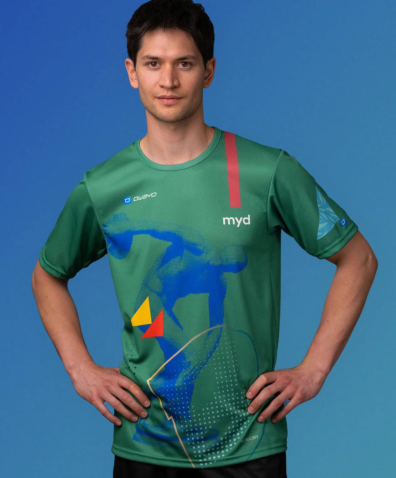 En mann i en grønn, tilpasset sportskjorte fra owayo med et blått, gult og rødt grafisk design og ordet 'myd' på brystet.