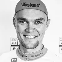En mann i sykkelutstyr med 'Wiesbauer'-logoen på lue og skjorte.