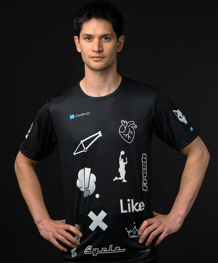 En mann har på seg en svart sporttrøye med ulike hvite symboler og logoer.