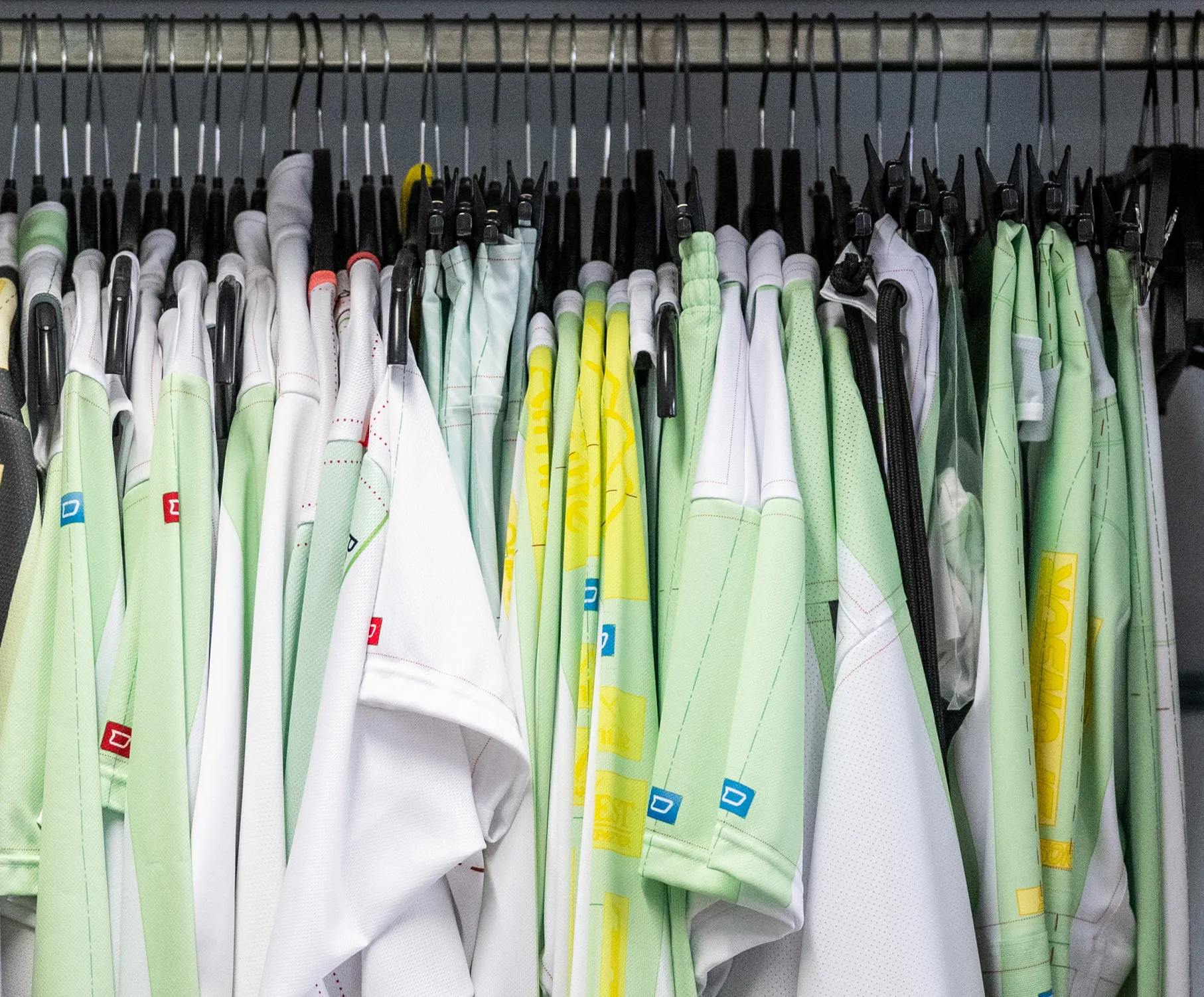 En utvalg av tilpasset sportsutstyr i ulike farger hengende på klesstenger.