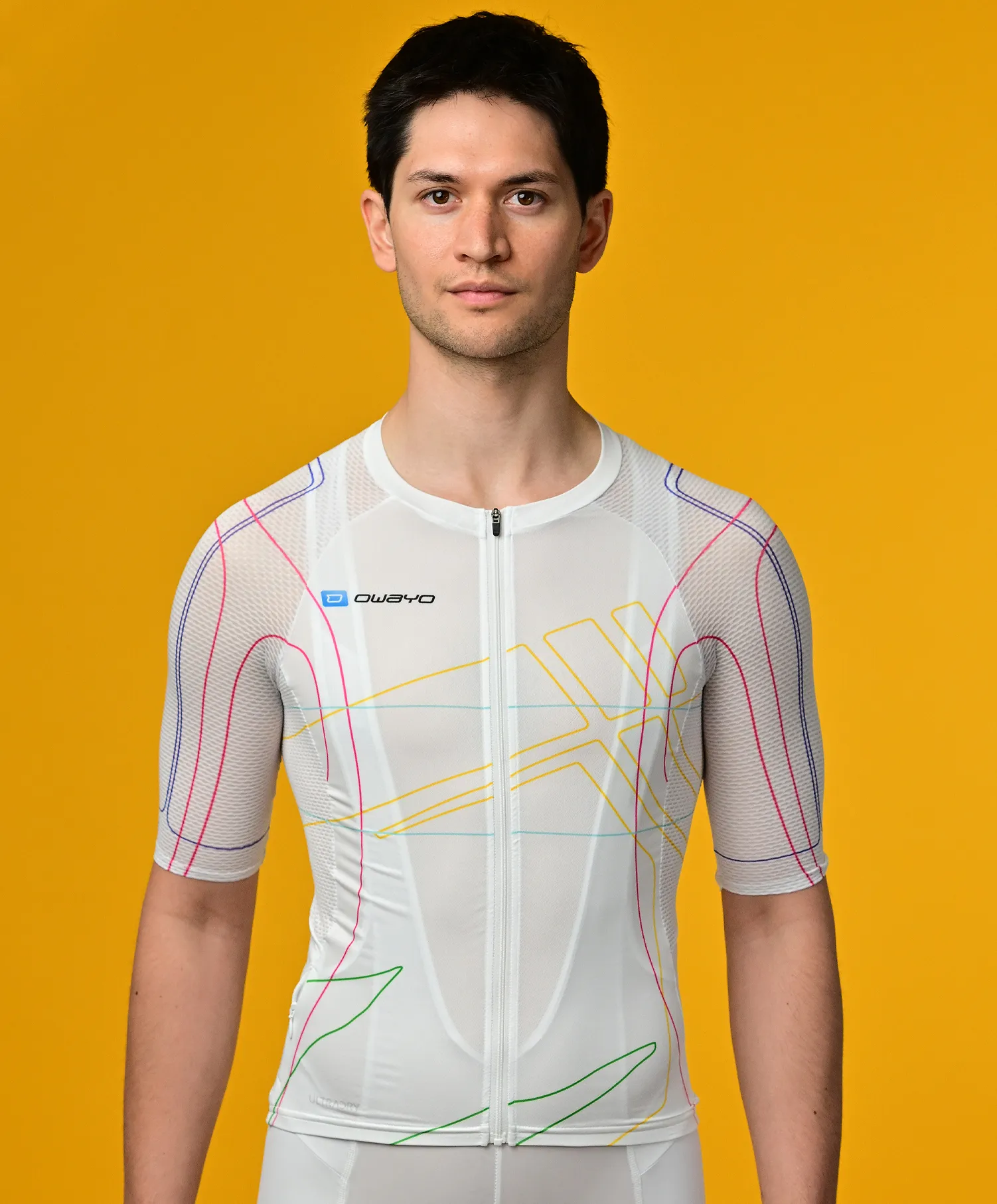 En mann bærer en hvit, kortermet, sporttrøye med fargerike linjer fra owayo foran en gul bakgrunn.
